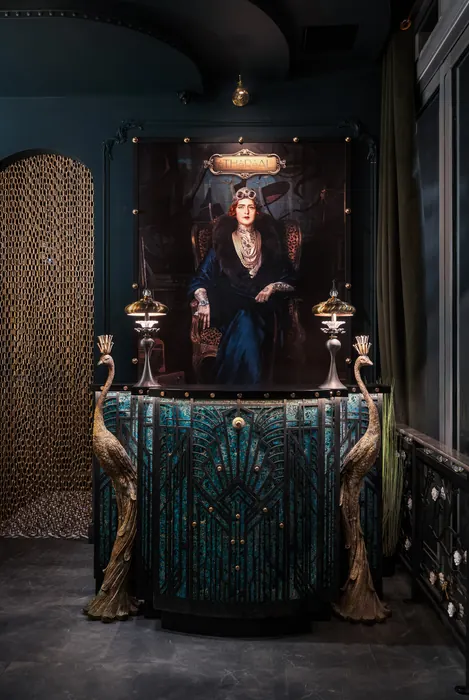 The host stand beneath a framed portrait at the entrance