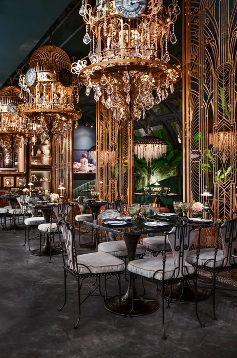 Rows of dining tables lit by tiered crystal chandeliers