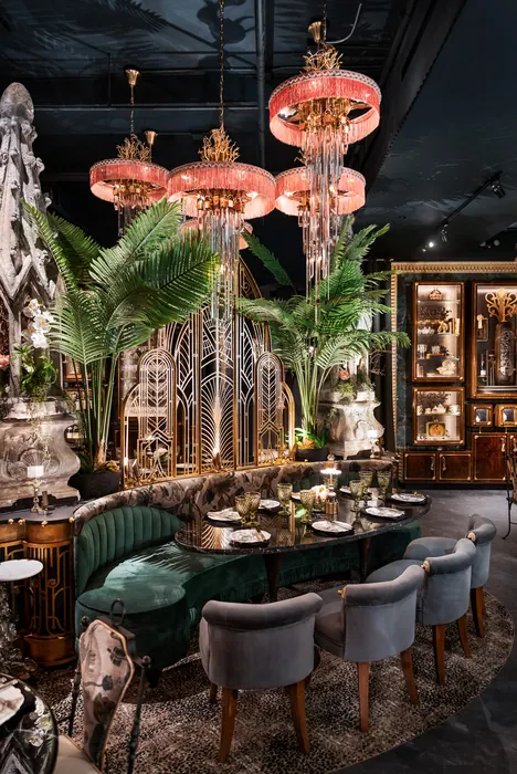 Rose-tinted pendant lamps above a dining table dressed with greenery