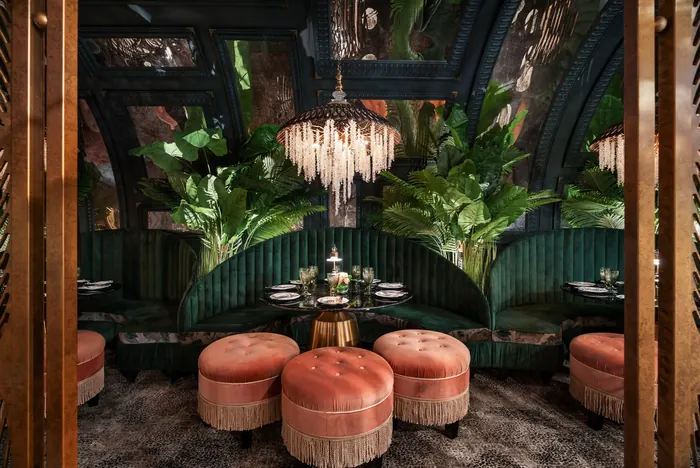 Symmetrical banquette alcove with coral ottomans and palm fronds