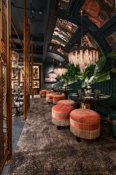 Dining tables and coral seating framed by a gilded screen