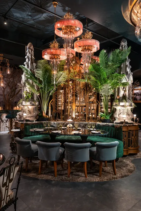 Teal upholstered chairs beneath rose glass lanterns and palm fronds