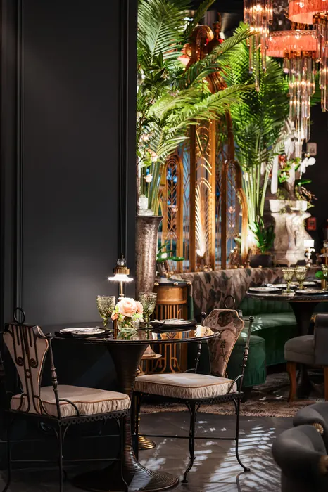 A small table and chairs framed by ferns and gilded columns