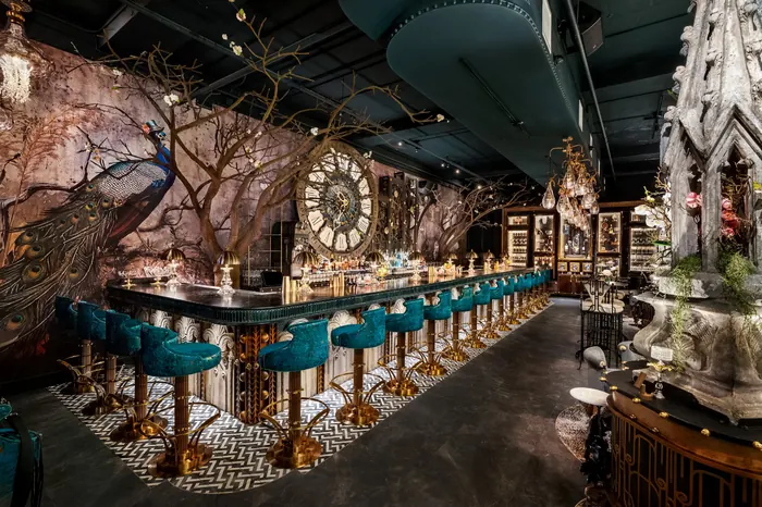 Teal bar stools along the counter, peacock mural and mosaic clock behind