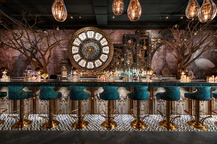 The bar seen head-on, mosaic clock and painted branches filling the wall